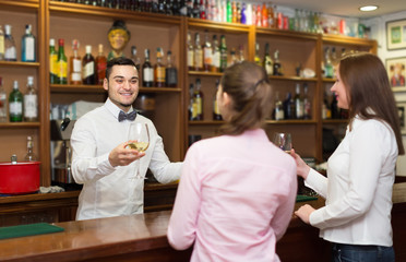 Two girls flirting with barman .