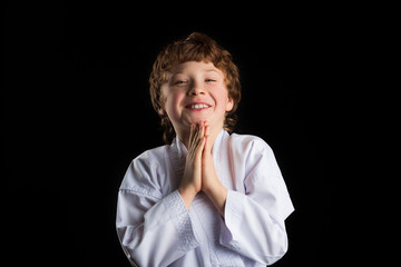 Smiling karate boy in white kimono isolated on black background