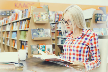 Girl reading books in library/ bookshop