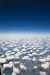 Blick aus einem Flugzeug auf die Erde mit Cummulus Wolken