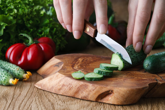 Cutting vegetables on a wooden board, close up view