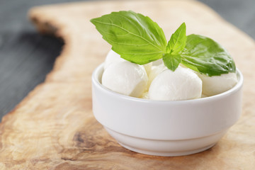 small balls of mozzarella in bowl with basil