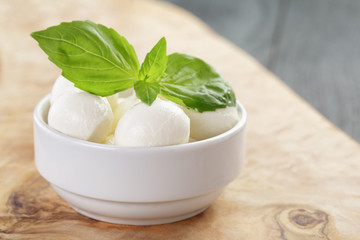small balls of mozzarella in bowl with basil