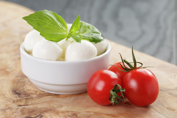 small balls of mozzarella in bowl with basil