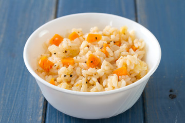 rice with vegetables in white bowl on blue wooden background