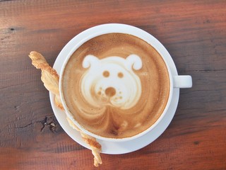 Latte Coffee art "Dog Face" and biscuit stick on the wooden desk.