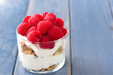 fresh dessert wuth raspberries in glass in blue wooden background