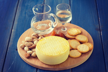 cheese with cookies, nuts and wine on tray on blue background