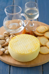 cheese with cookies, nuts and wine on tray on blue wooden background
