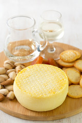 cheese with cookies, nuts and wine on tray on white background