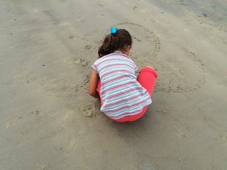 Fototapeta na wymiar niña dibujando un corazon en la arena
