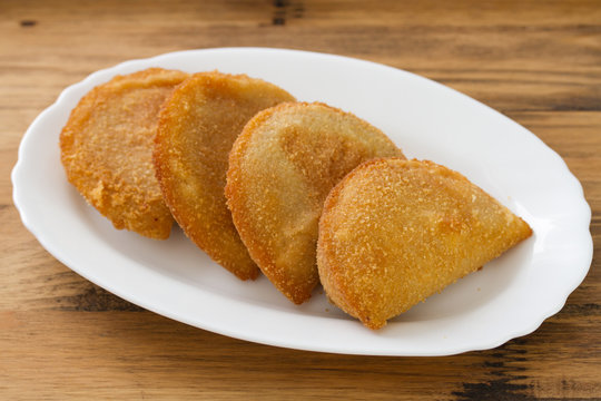 portuguese meat cookies on white dish on brown background