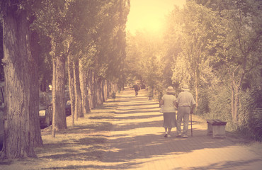 Vintage photo of old couple walking in the park - obrazy, fototapety, plakaty