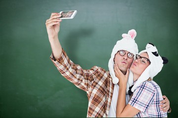 Composite image of geeky hipster couple taking selfie 