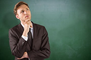 Composite image of young businessman thinking with hand on chin