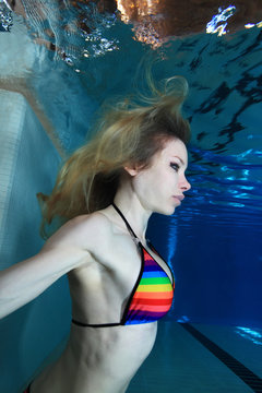 Young woman posing underwater in the pool 