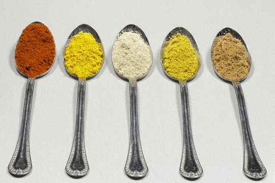 Tablespoons of different types of spice powders and food coloring