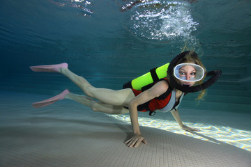 Female scuba diver with neoprene swimsuit diving underwater in the pool 