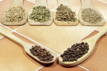 Black pepper and cloves, with several kinds of aromatic dried herbs behind