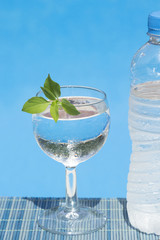 Glass and bottle of water on bamboo straw mat – poolside