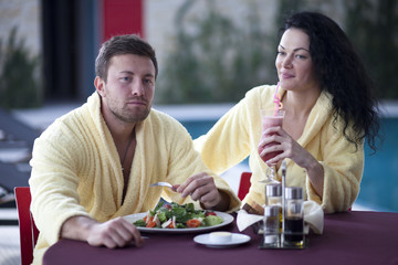 Cute couple in bathrobes having breakfast together at hotel