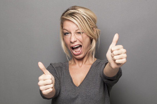 satisfaction concept - thrilled young blonde woman giving a double thumb up for agreement