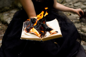 A woman holds black burning book 