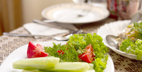 Lettuce, tomato, cucumber on a white plate on a table in a restaurant
