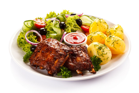 Grilled ribs, French fries and vegetables on white background 