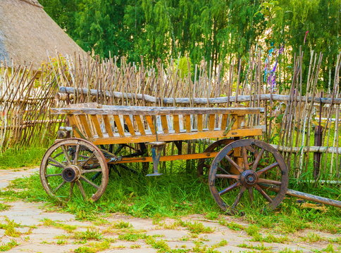 Old wooden cart on the lawn near the fence