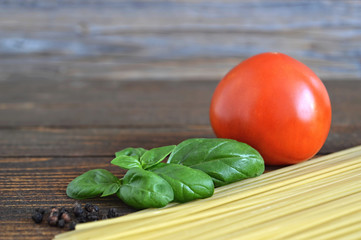  Spaghetti, fresh tomato and basil leaves on wooden background
