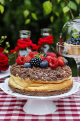 Cheesecake with chocolate topping decorated with summer fruits