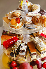 Assorted cakes, cookies and fruits on glass cake stand
