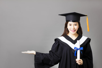 beautiful young  graduate holding diploma with showing gesture