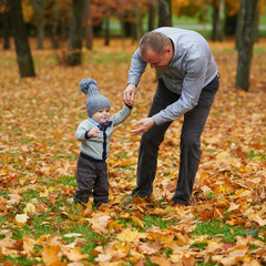 father with son walking in autumn forest