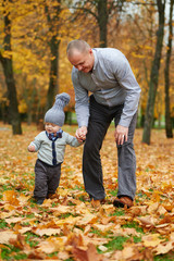 Naklejka na ściany i meble father with son walking in autumn forest