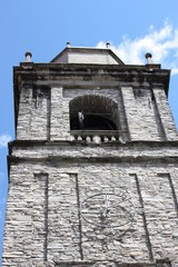Church bell tower in the old town Bellagio at Lake Como under blue sky, Italy 