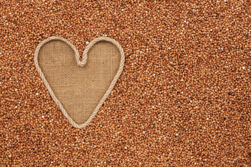 Symbolic heart made of rope lies on sackcloth and  buckwheat gra
