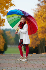 Obraz premium girl under rainbow umbrella in autumn park