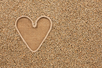 The symbolic heart made of rope lies on sackcloth and rye grains