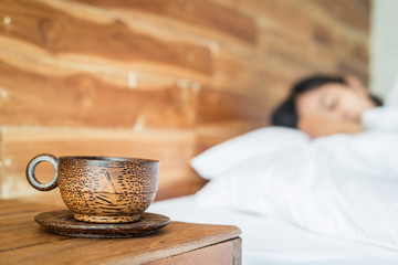 Wood coffee cup on table and women on the bed