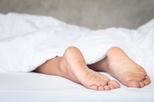Feet of women on white bedding in the morning time