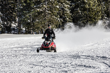 Young man on snowmobile at beautiful winter day