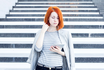 Business woman with a tablet in hands looking down on the background of the stairs in the business center