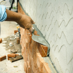 Applying construction trowel with brick wall