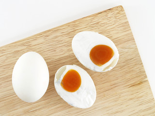 overhead view of salted eggs on a wooden cutting board isolated on white
