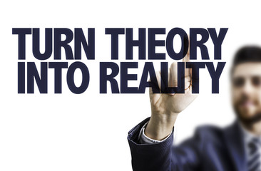 Business man pointing the text: Turn Theory Into Reality