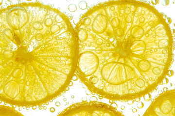 Fresh lemon slice in water with bubbles on white background