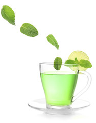 Mint leaves falling in cup of green tea isolated on white