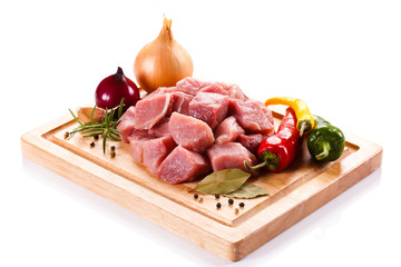 Raw pork chops on cutting board and vegetables 
